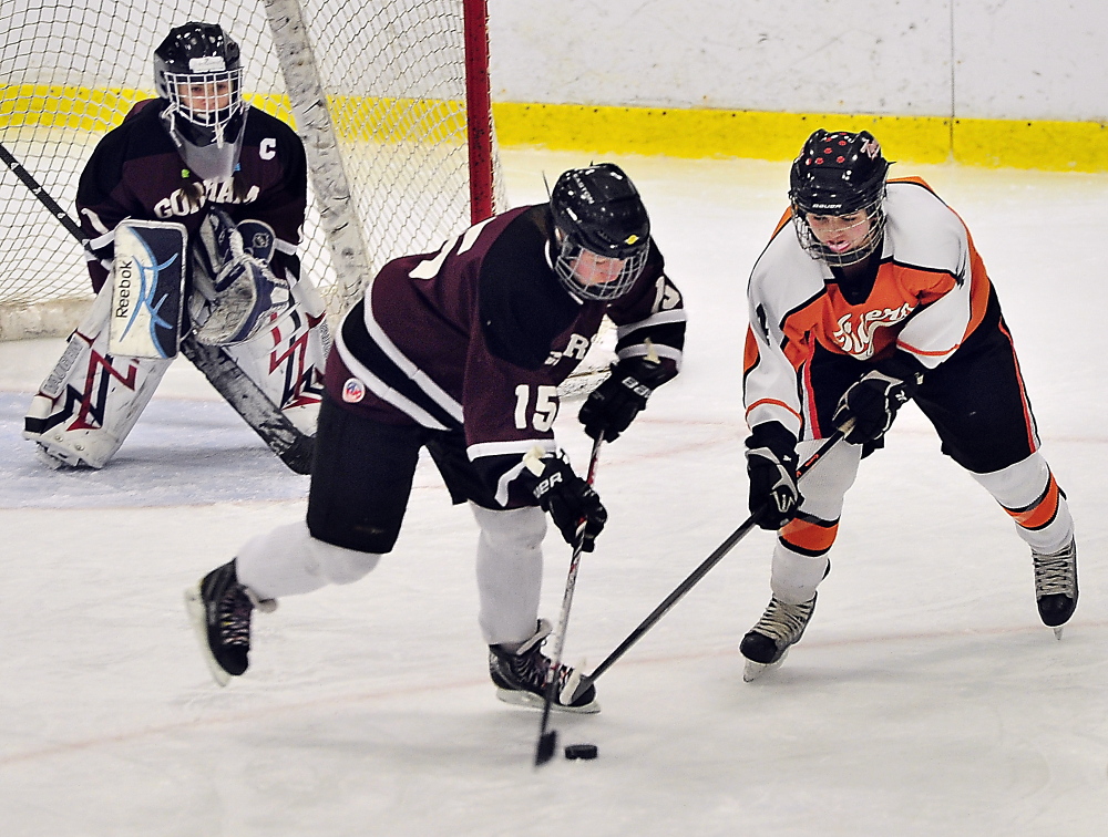 Megan Demers, center, of Gorham/Bonny Eagle battles for the puck with Biddeford’s Katherine Dumoulin as Gorham/Bonny Eagle goalie Maddy Hamblen looks on Saturday at Biddeford Ice Arena. Dumoulin scored her second goal of the game 17 seconds into overtime to give Biddeford a 3-2 win.