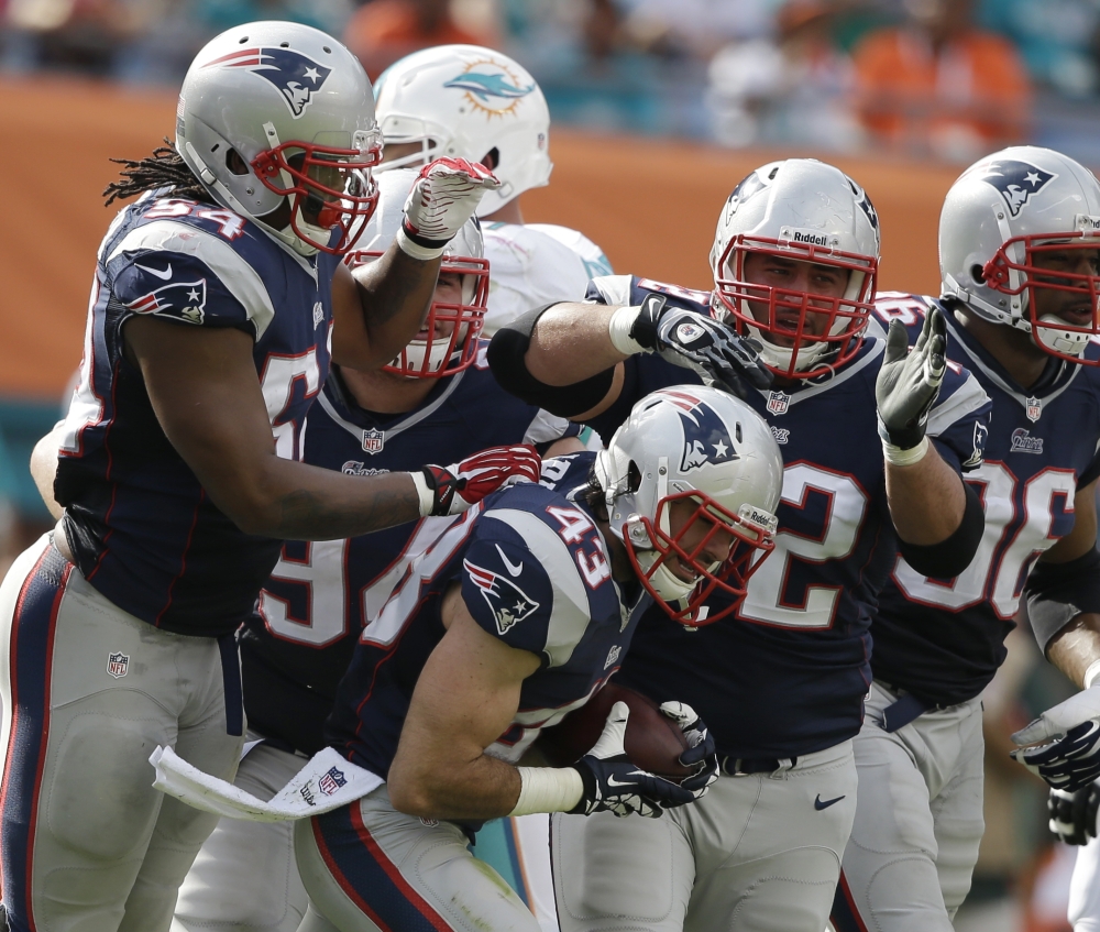 New England Patriots defensive back Nate Ebner (43), center, is congratulated by his teammates, Dont’a Hightower (54) and defensive end Jake Bequette (92), after Ebner recovered a fumbled field goal by the Miami Dolphins during the first half of Sunday’s game.