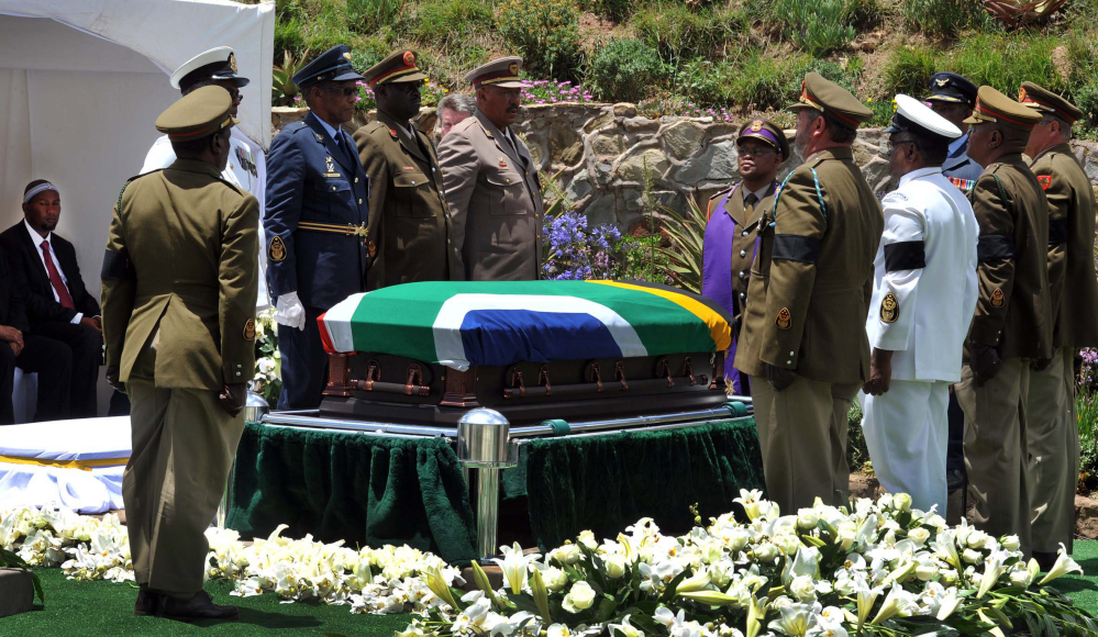Military soldiers stand at attention over South African President Nelson Madela’s casket before his burial in his home village of Qunu, South Africa, Sunday, Dec. 15, 2013.