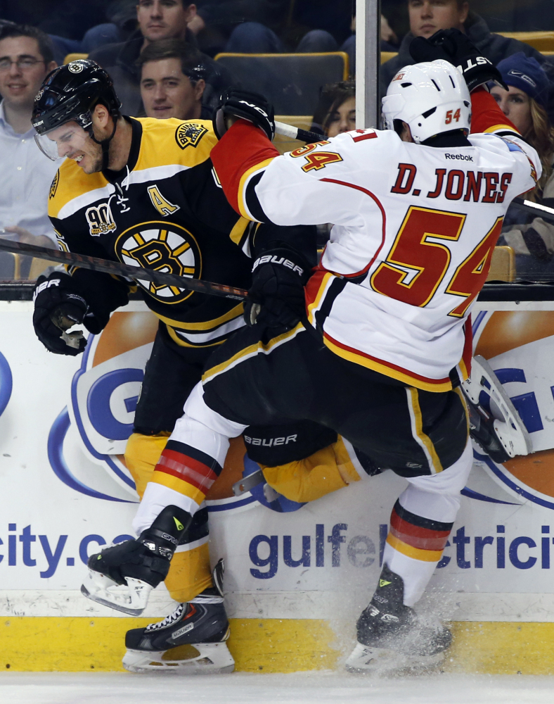 Boston Bruins center David Krejci collides with Calgary Flames right wing David Jones along the boards in Boston Tuesday night.