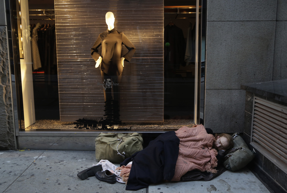 A destitute man sleeps on the sidewalk under a holiday window at Blanc de Chine in New York in November. The growing gap between the richest Americans and everyone else is hurting the U.S. economy, say a majority of more than three dozen economists surveyed this month by The Associated Press.