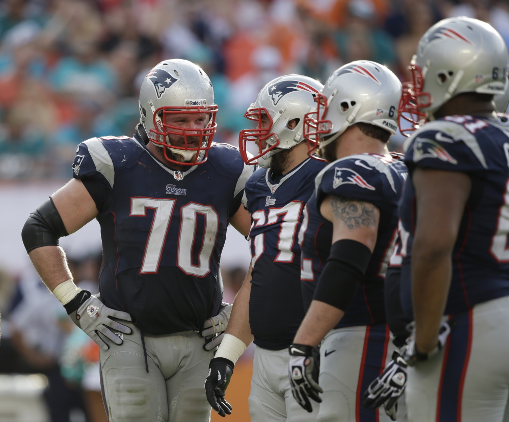 New England Patriots guard Logan Mankins, left, talks to teammates on the field Sunday during a break in the second half of their game against the Miami Dolphins.