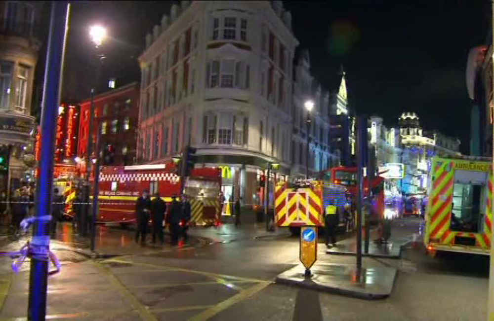 This image taken from television shows emergency services attending an incident at the Apollo Theatre, illuminated at rear right, on London’s Shaftesbury Avenue, Thursday evening, Dec. 19, 2013, during a performance at the height of the Christmas season, with police saying there were “a number” of casualties. It wasn’t immediately clear if the roof, ceiling or balcony collapsed during a performance.