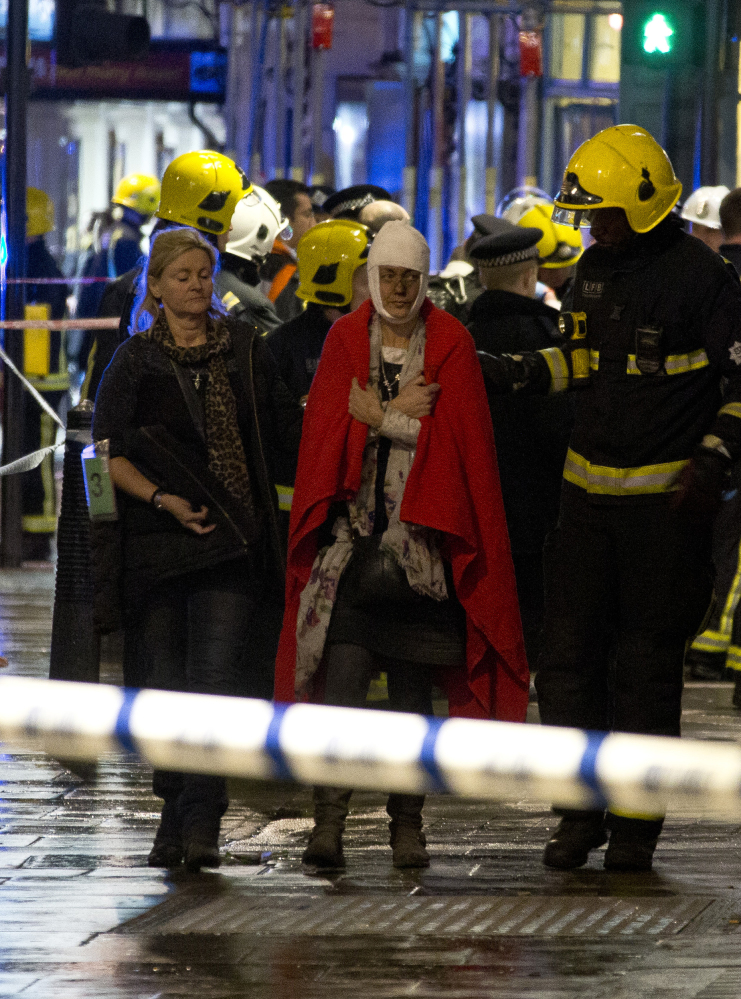 A woman walks, bandaged and wearing a blanket given by emergency services, following an incident at the Apollo Theatre, in London’s Shaftesbury Avenue, Thursday evening, Dec. 19, 2013, during a performance at the height of the Christmas season, with police saying there were “a number” of casualties. It wasn’t immediately clear if the roof, ceiling or balcony had collapsed during a performance. Police said they “are aware of a number of casualties,” but had no further details.