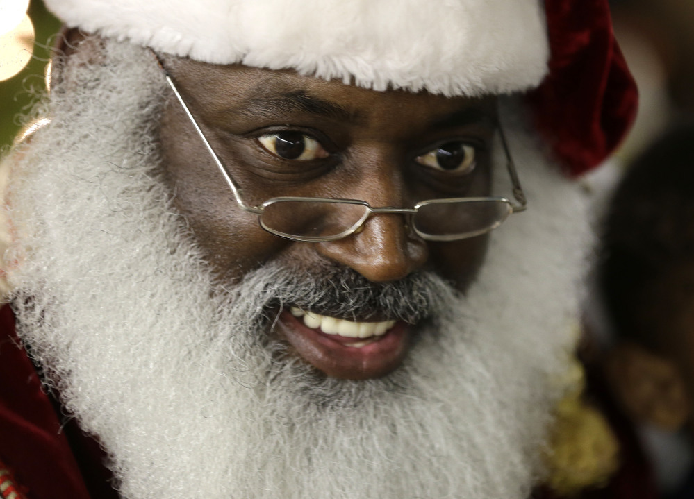 Dee Sinclair, portraying Santa Claus, reads a story to children in Atlanta on Tuesday. “Kids don’t see color. They see a fat guy in a red suit giving toys,” said Sinclair, 50, who bills himself as the “Real Black Santa.”