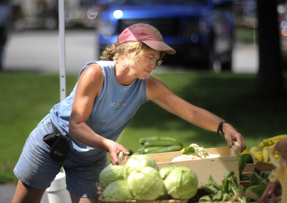 Cathy Karonis, who with husband Pete Karonis owns Fairwinds Farm in Topsham, works at the South Portland farmer’s market in August. Pete Karonis said he welcomed a federal decision to back off stricter rules on produce safety.