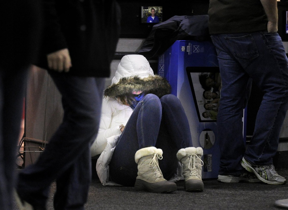 Amy Barham of South Portland sits on the floor of Best Buy early Nov. 23, 2012, while waiting for others to finish shopping.