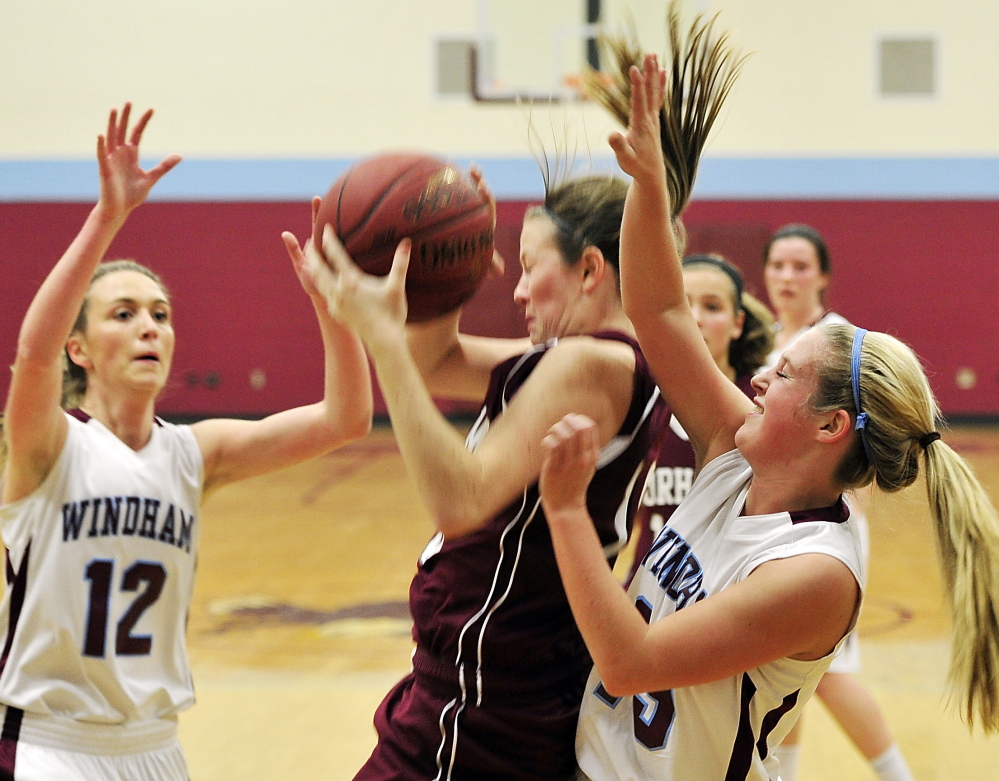 Jessica Rexrode of Gorham pulls down a rebound between Windham’s Sam Frost, left, and Macy Mannette during an SMAA basketball game Friday night in Windham. Windham won in overtime, 40-39.