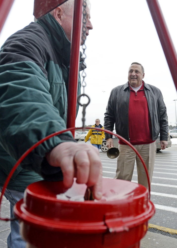 A shopper drops money into the Salvation Army kettle as Gov. Paul LePage rings the bell at Walmart in Biddeford on Friday.