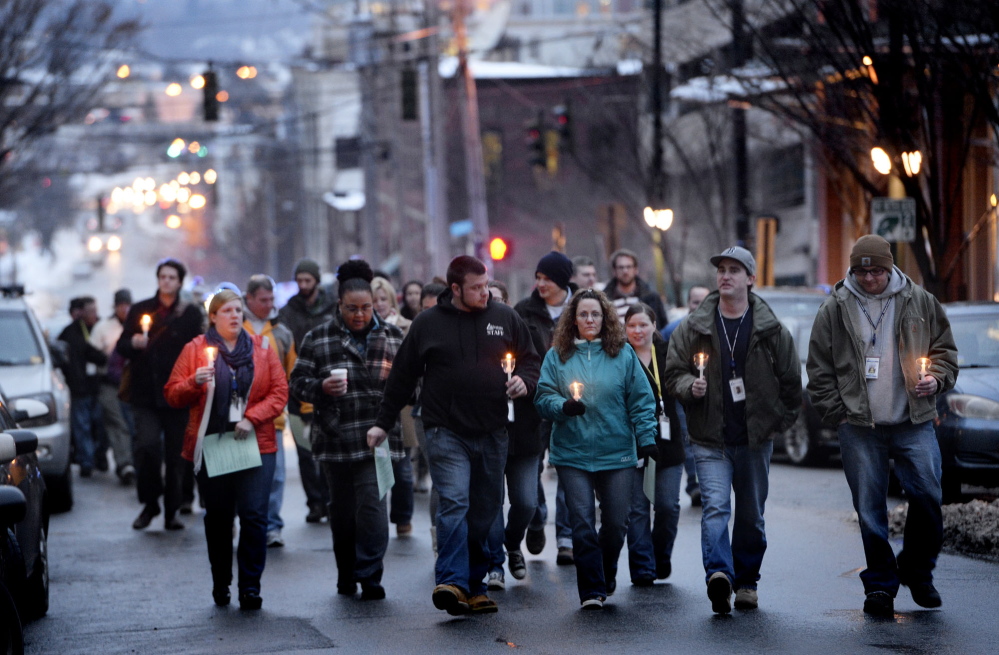 People proceed up Preble Street toward Monument Square in Portland on Friday for the annual memorial vigil. Twenty-one homeless people died while living on the city’s streets this year, compared with 30 last year.
