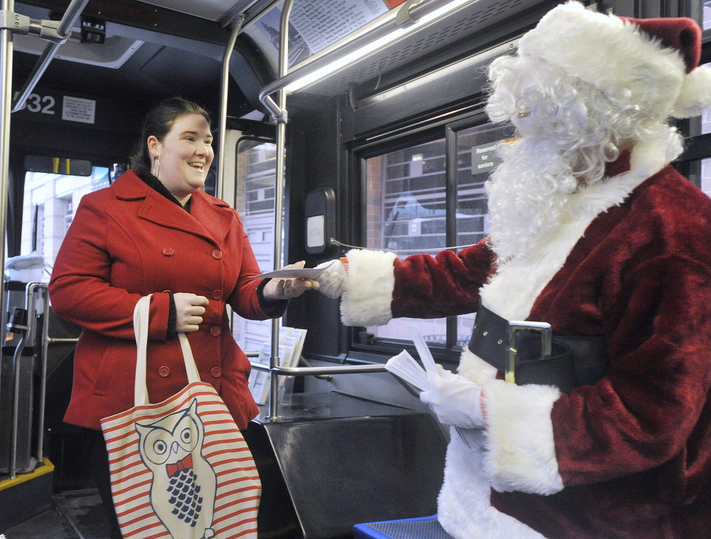 Britney Mitchell accepts a $100 bill from Secret Santa as she boards a Metro bus in Portland on Friday.