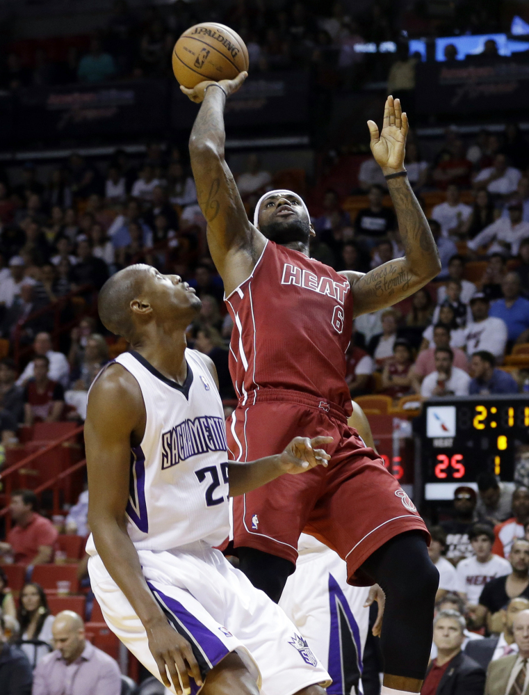Miami’s LeBron James shoots over Sacramento’s Travis Outlaw in the first half of Friday’s game in Miami, won by the Heat, 112-103.