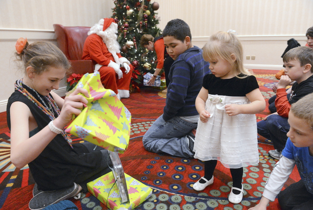 Children involved with Grandparents Raising Grandchildren Support Group unwrap gifts at the group’s recent Christmas party at the Mystic Marriott in Groton, Conn.
