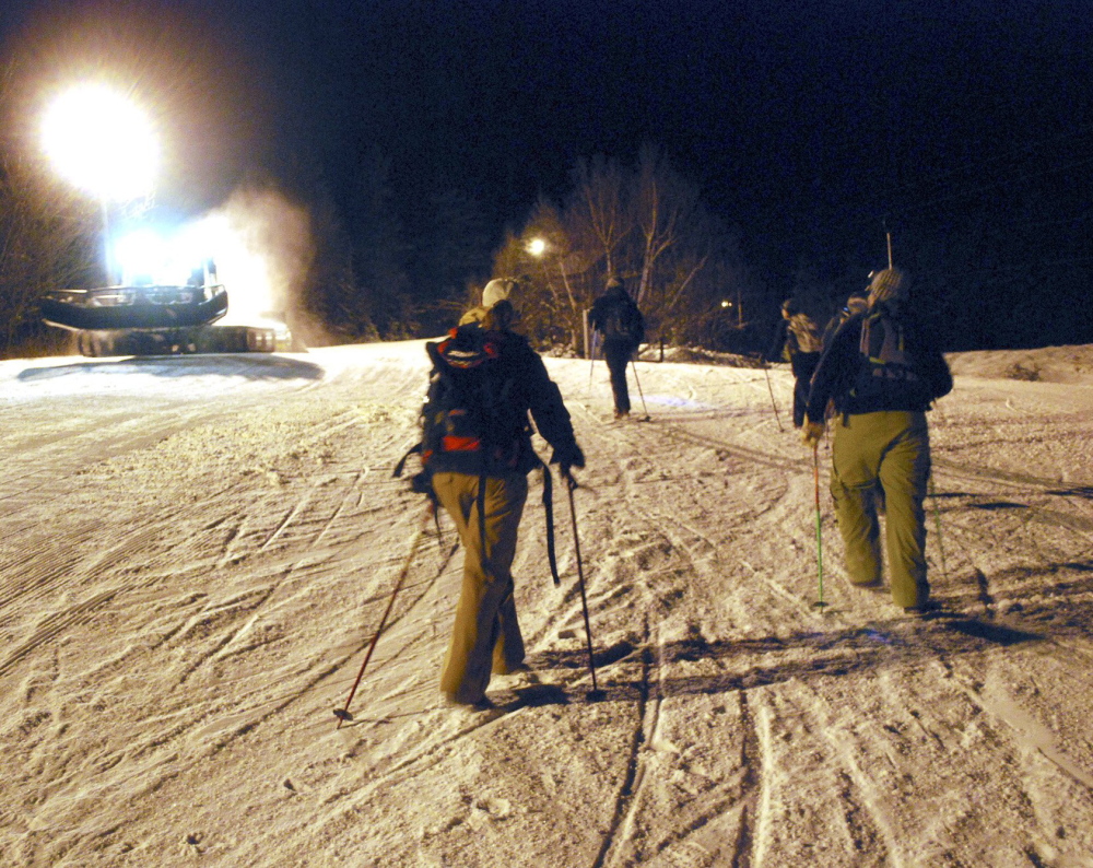Several skiers head out on the Full Moon Hike up Mt. Abram. At left is a grooming machine that brings their ski equipment up to the top, and from there, well ... it’s all downhill.