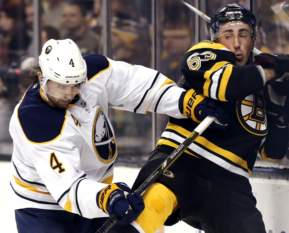 Buffalo’s Jamie McBain checks Boston’s Brad Marchand into the boards during the second period of Saturday’s game in Boston, won by the Bruins 4-1.