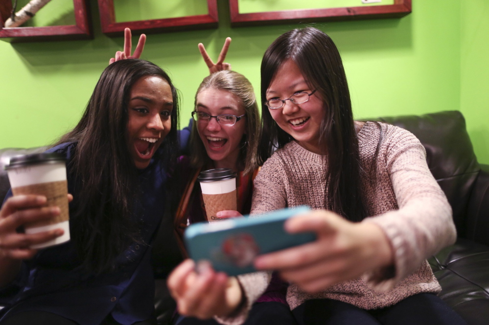 Amrita Mohanty, 16, from left, Marta Williams, 16, and Michelle Mao, 15, take a Snapchat “selfie” while having coffee Dec. 12 at the Steepery Tea Bar in Woodbury, Minn. The ubiquitous smartphone is causing a decline in sales of digital cameras.