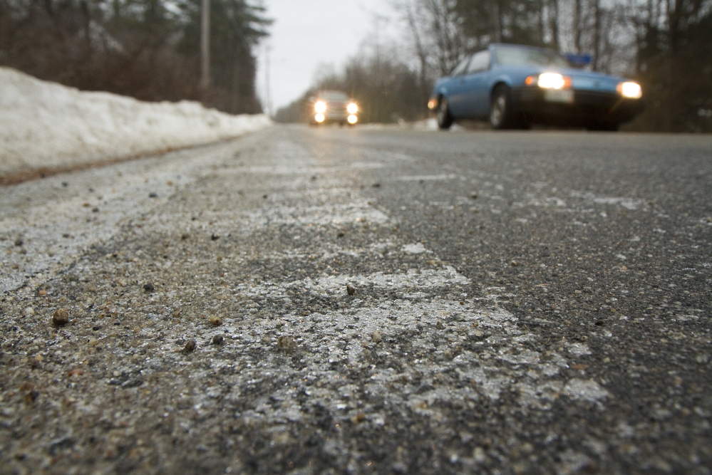 Ice builds up on the edge of the road as cars pass by on a treated, ice-free Saco Road in Standish on Sunday.