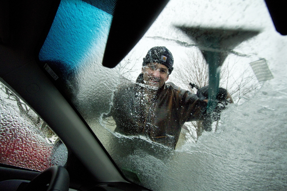 Mark Storck scrapes ice from the windshield of his car in Bridgton on Sunday.
