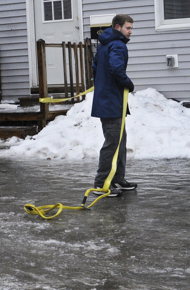 Antonio Sirabella holds on to a tow strap Sunday while attempting to walk through the parking lot of his Gardiner apartment building. More than a quarter-inch of ice coated tree branches and wires in the Augusta and Gardiner areas at noon.