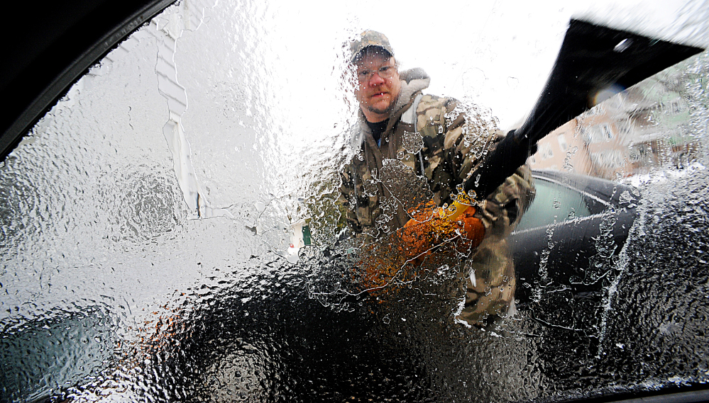 Charles Winslow clears ice off of his car in Lewiston on Sunday. Ice build-up on tree limbs brought down power lines in northern New England, leaving thousands of homes and business in Vermont and Maine without electricity.