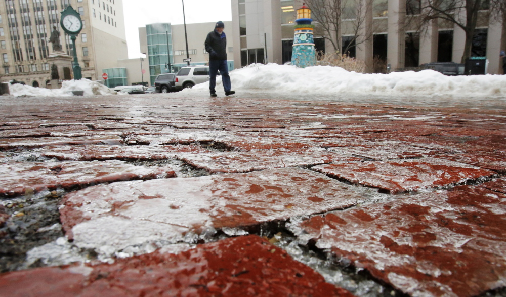 A man walks down the ice-covered brick courtyard of One City Center in Portland on Monday. Sidewalks became coated with ice on Monday, causing pedestrians to shuffle instead of stride through the city.