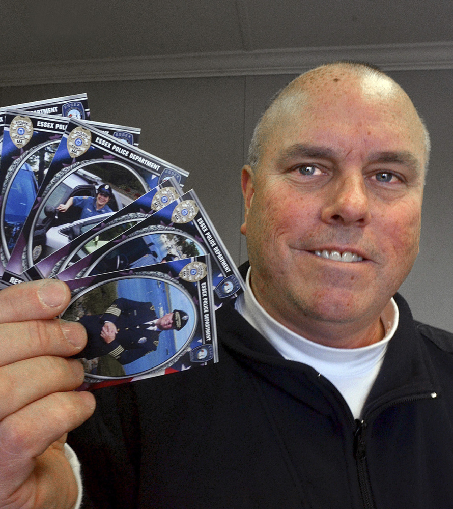Police Chief Peter G. Silva holds trading cards depicting police officers at headquarters in Essex, Mass.