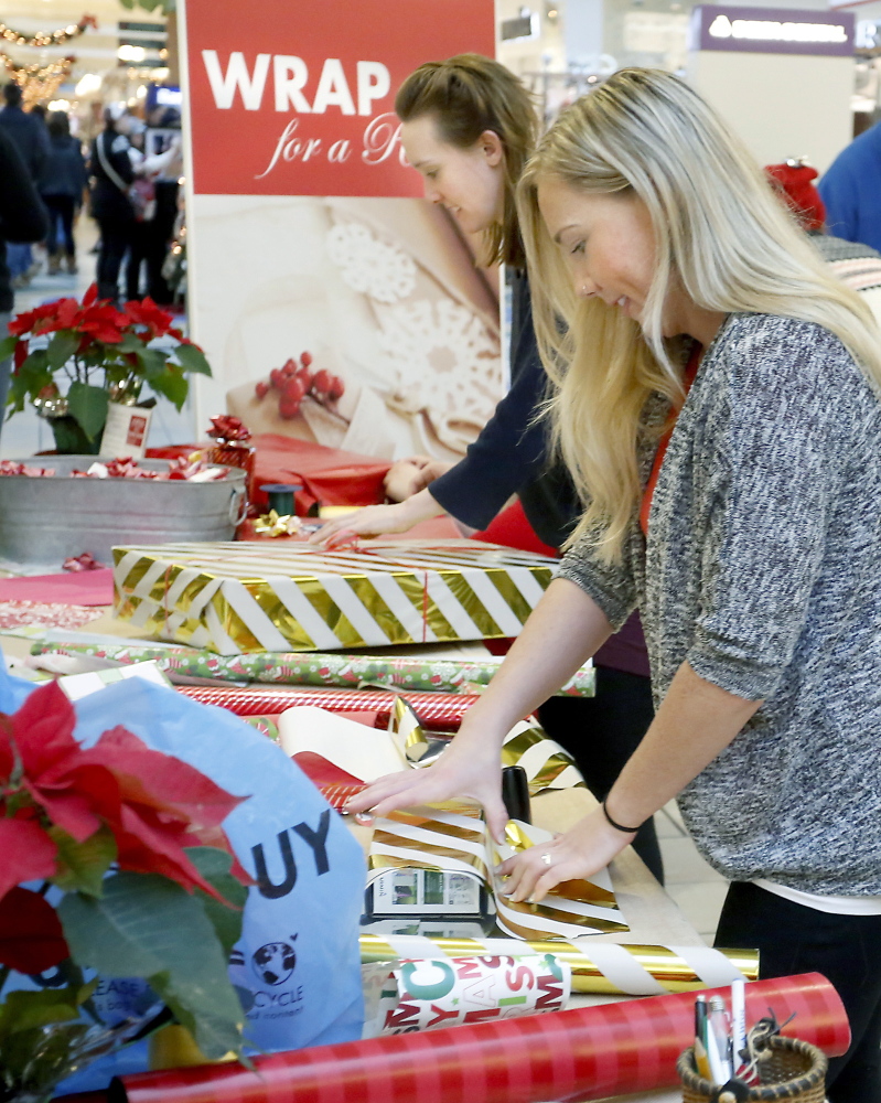 Volunteers Joanna Weathers, foreground, and April Singley, both teachers at the NorthStar Learning Center, wrap gifts Monday for shoppers at The Maine Mall as part of the Wrap for a Reason fundraiser.
