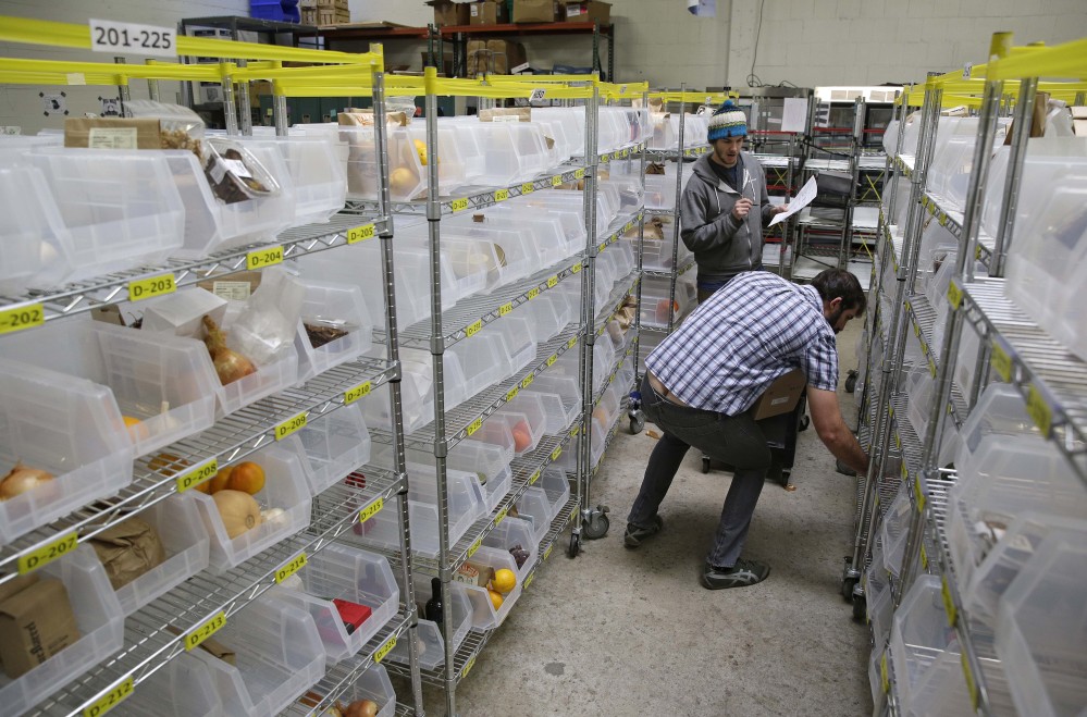 Jesse Hayter, front, and Josh Greenfield fill customer’s order bins at the Good Eggs warehouse in San Francisco.