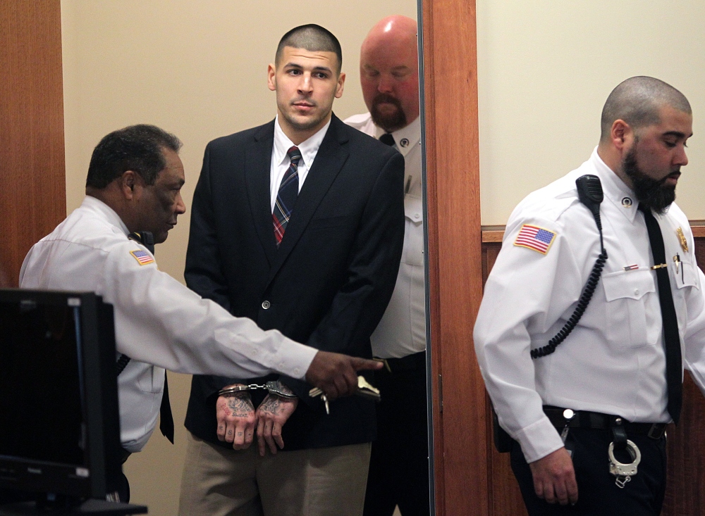 Former New England Patriots NFL football player Aaron Hernandez is led into his court appearance at the Fall River Superior Court in Fall River, Mass., Monday, Dec. 23, 2013. A Massachusetts judge may impose a formal gag order in the murder case against Hernandez, after his attorneys accused the state of allowing leaks that jeopardize his right to a fair trial.