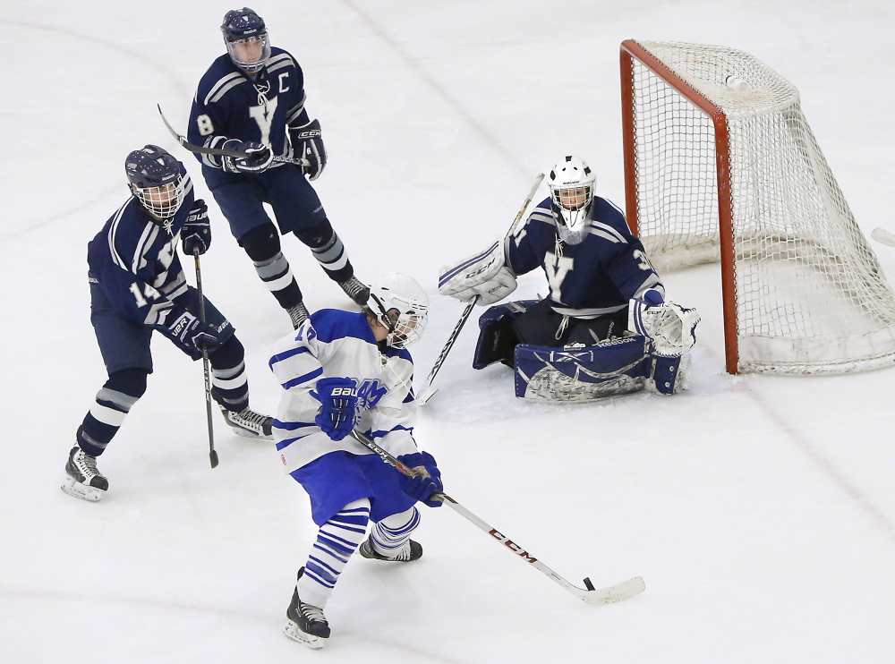 James Ross of Kennebunk prepares to take a shot against Yarmouth goalie Nick Allen while Max Watson, left, and Brian Travers defend during a Class B hockey game Monday afternoon at the University of New England’s Alfond Forum. The game ended in a 1-1 tie.