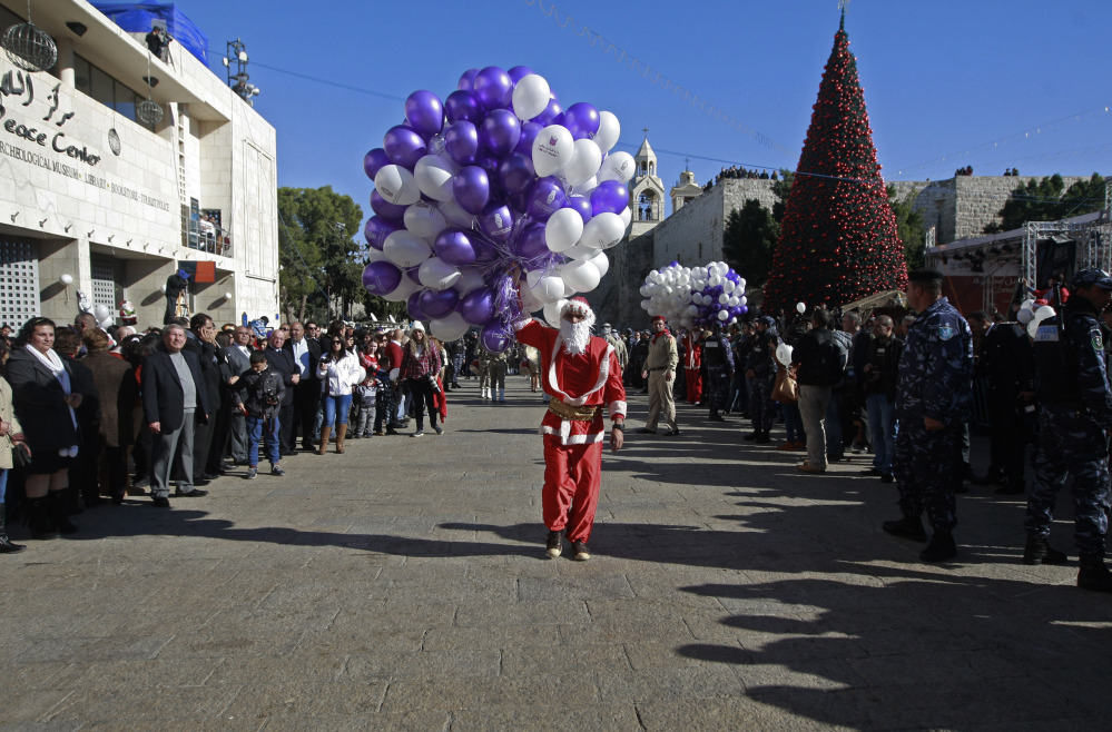 A Palestinian youth dressed as Santa Claus holds balloons at Manger Square, outside the Church of the Nativity, traditionally believed by Christians to be the birthplace of Jesus Christ, in the West Bank town of Bethlehem on Tuesday.