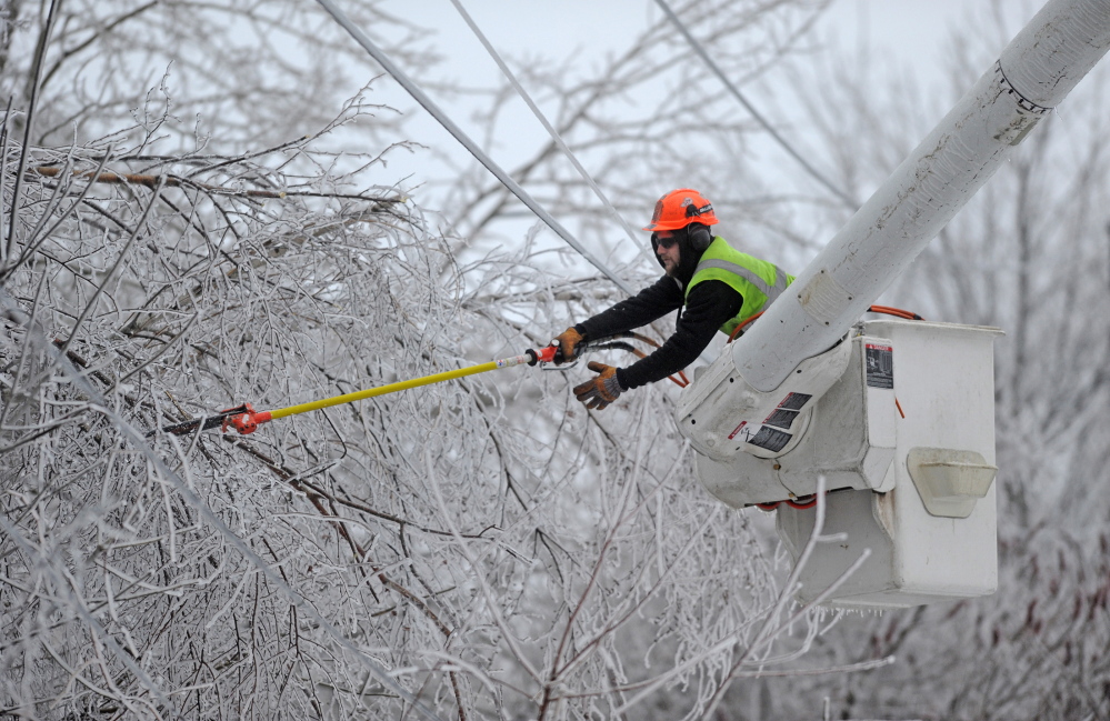 Andrew Powers, an arborist with Asplundh Tree Experts, clears power lines from iced branches along Mayflower Heights Drive in Waterville on Monday. Kennebec County led the way with about 34,500 outages, or more than half of all CMP customers in that county.