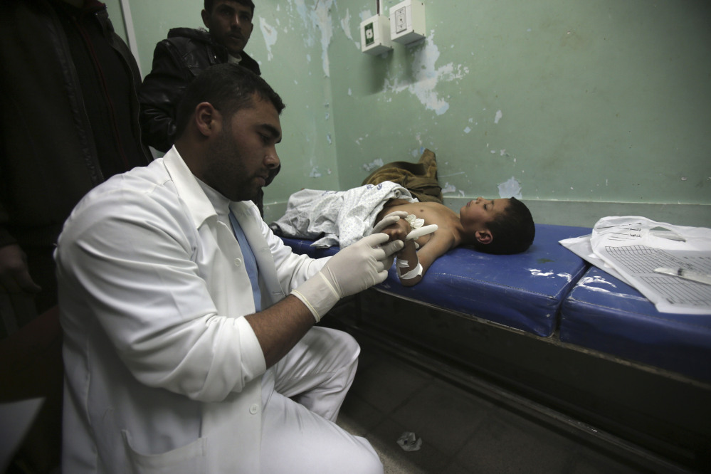 A Palestinian doctor treats a child, who medics said was wounded by shrapnel during an Israeli air strike on the Al Maghazi camp, at treatment room of Al-Aqsa hospital in Deir Al Balah, central Gaza Strip, Tuesday.