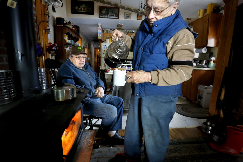 Elsa Seeger pours a cup of coffee that she keeps warm with their wood stove as her husband Robert Seeger warms next to the stove they have been using for heat and cooking when they don’t have electricity in their home in Jefferson on Tuesday afternoon, Dec. 24, 2013.