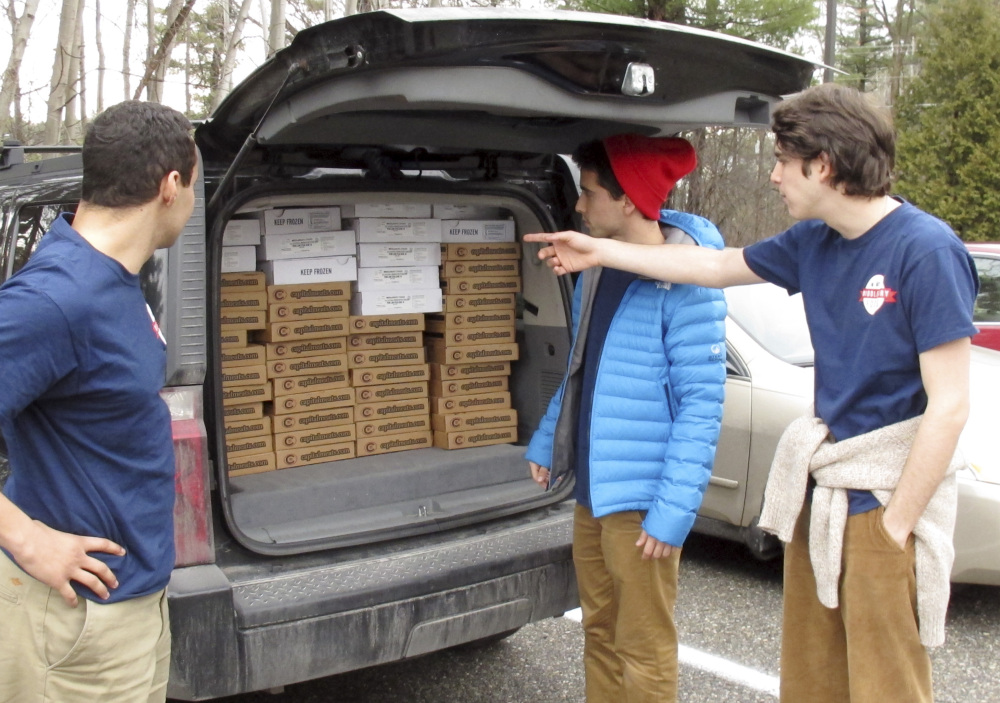 Middlebury College Students Elias Gilman, left, Eddie Danino-Beck, center, and Oliver Mayers prepare to unload frozen meat from the back of a van in Middlebury, Vt.