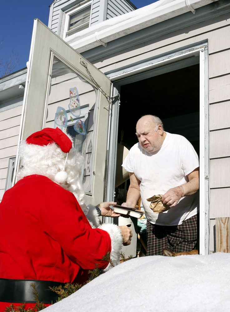 Volunteers Philip Rhinelander and his daughter Julia place food in a bag for Maxine Mooers at her home in Portland as part of the Southern Maine Agency on Aging’s Meals on Wheels program, which delivered hot meals to seniors on Christmas Day.