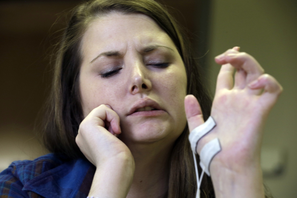 Double hand transplant recipient Lindsay Aronson Ess grimaces as she works on her dexterity during a physical therapy session in Richmond, Va. The government is preparing to regulate the new field of hand and face transplants.