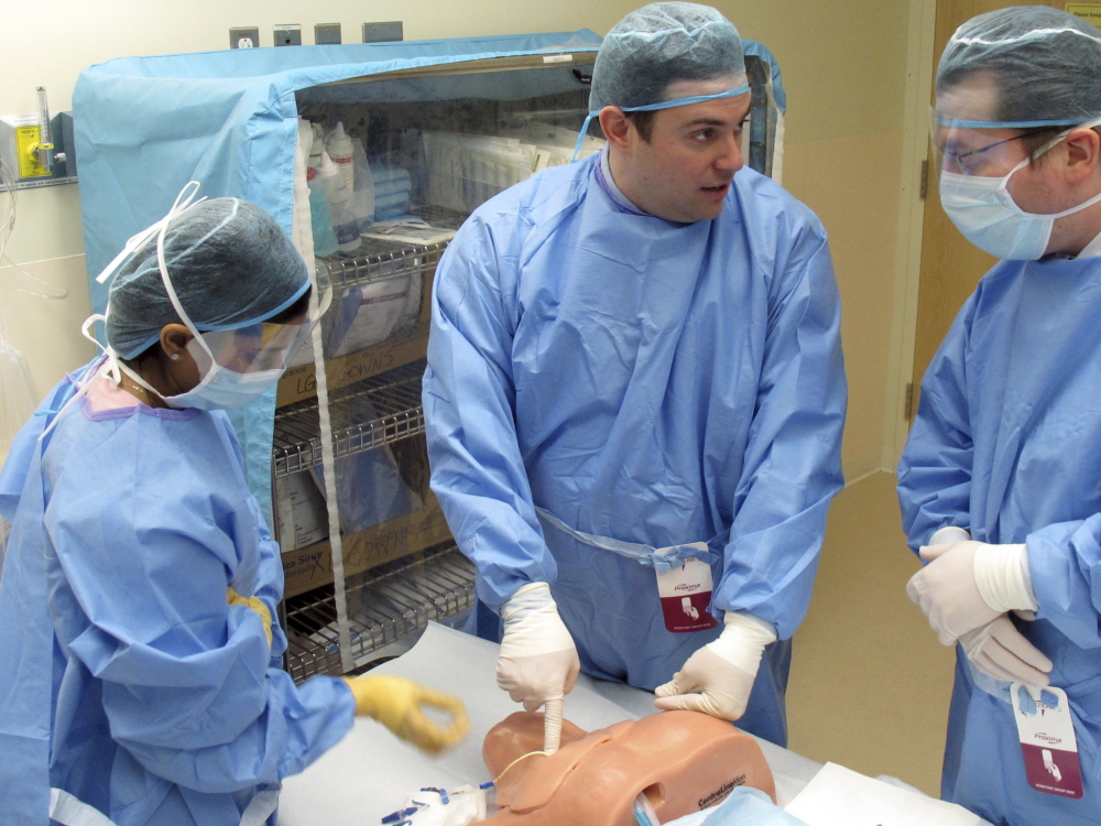 Dr. Alfred Croteau, center, a surgery resident at Fletcher Allen Health Care in Burlington, Vt., demonstrates, on Dec. 11, the proper procedure for inserting a central line to Drs. Jothi Kanagalingam, left, and Lucas Mikulic, right.