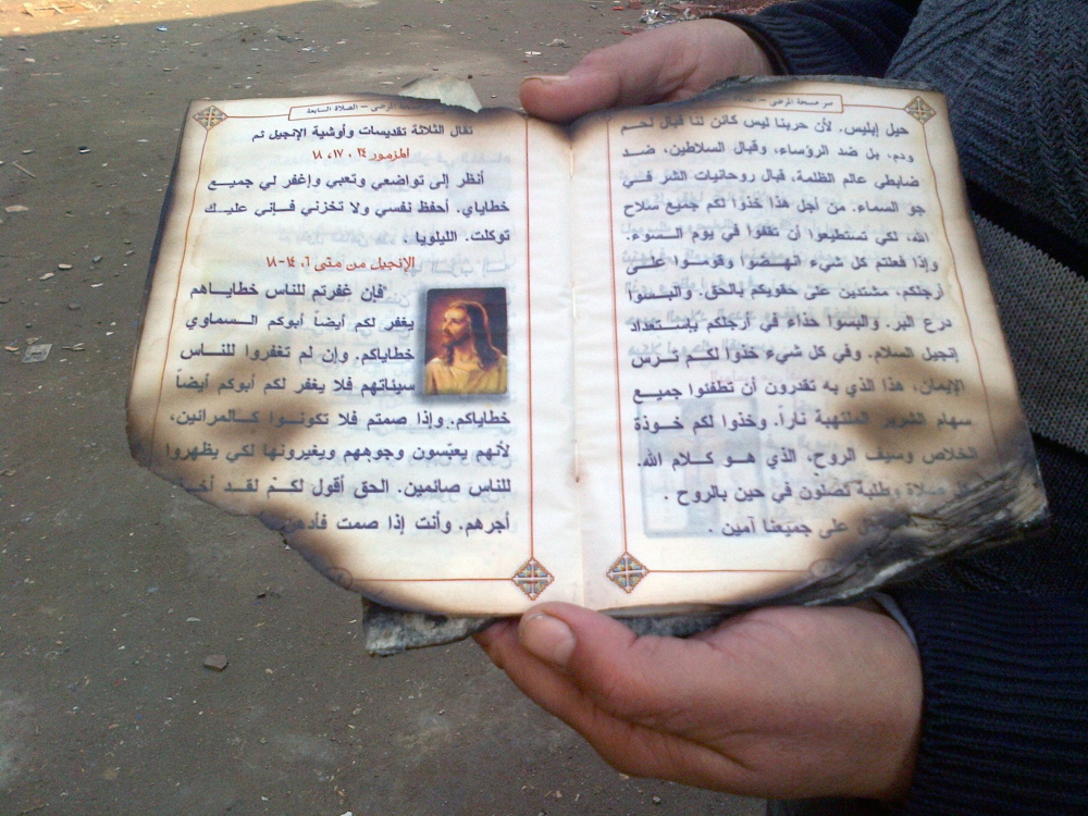 A parishioner holds a scorched Coptic prayer book, salvaged from an attack on the Church of the Archangel Michael in Kerdasa, Egypt, on Aug. 14.