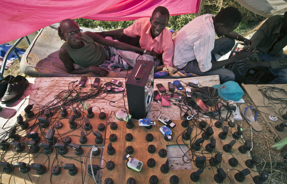 Displaced men run a mobile phone charging station enabling others to keep in contact with relatives, inside a United Nations compound which has become home to thousands of people displaced by the recent fighting, in Juba, South Sudan Friday, Dec. 27, 2013. Kenya’s president Uhuru Kenyatta on Friday urged South Sudan’s leaders to resolve their political differences peacefully and to stop the violence that has displaced more than 120,000 people in the world’s newest country, citing the example of the late Nelson Mandela and saying there is “a very small window of opportunity to secure peace” in the country where fighting since Dec. 15 has raised fears of full-blown civil war.