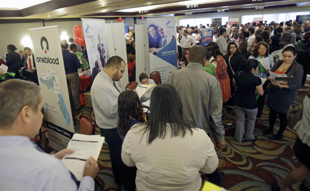 This Aug. 14, 2013 file photo shows job seekers checking out companies at a job fair in Miami Lakes, Fla. More than 1 million Americans are bracing for a harrowing, post-Christmas jolt as federal unemployment benefits come to a sudden halt this weekend. The development entails potentially significant implications for the recovering U.S. economy and sets up a tense battle when Congress reconvenes in the new year.