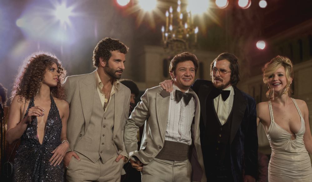 This film image released by Sony Pictures shows, from left, Amy Adams, as Sydney Prosser, Bradley Cooper, as Richie Dimaso , Jeremy Renner, as Mayor Carmine Polito, Christian Bale as Irving Rosenfeld, and Jennifer Lawrence as Rosalyn Rosenfeld, in a scene from “American Hustle.” From Baleís burgundy velour blazer to Adamsí plunging sequin halter dress, the film is a cinematic romp through the over-the-top styles of the late 1970s. Hair is so prominent in the picture, itís practically another character.