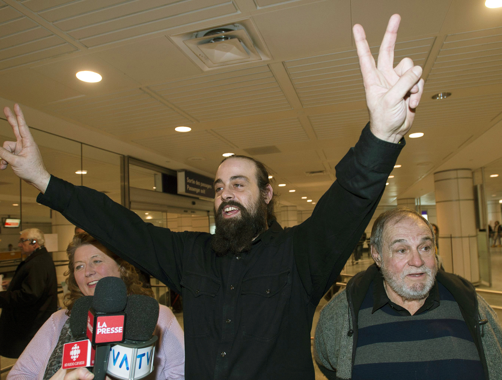Greenpeace activist Canadian Alexandre Paul, flanked by his parents Nicole and Raymond in Montreal, signals victory.