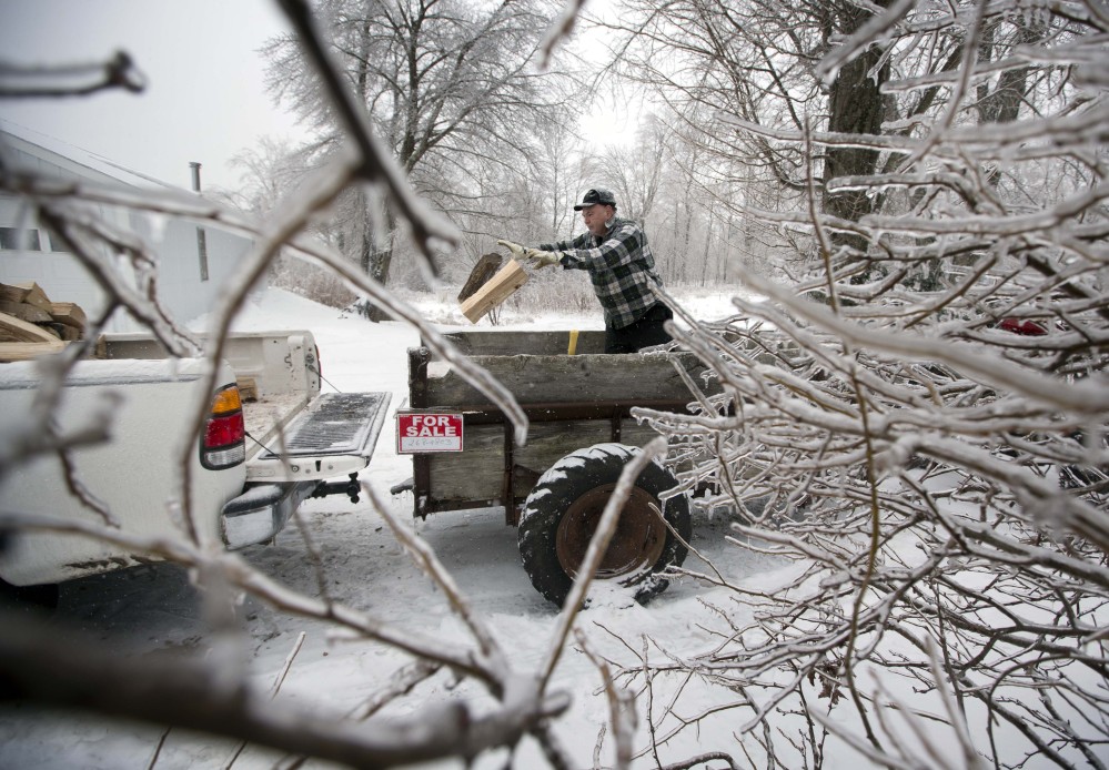 Ice from Monday’s storm still clings to branches as Ken Finnegan loads his truck with firewood Thursday in Litchfield. With electricity out, some Maine residents seek alternative ways to heat their homes.
