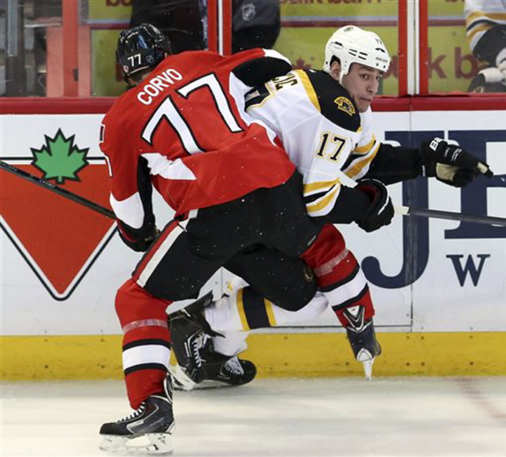 Boston Bruins’ Milan Lucic is checked by Ottawa Senators’ Joe Corvo during the first period of Saturday night’s NHL game in Ottawa, Ontario.