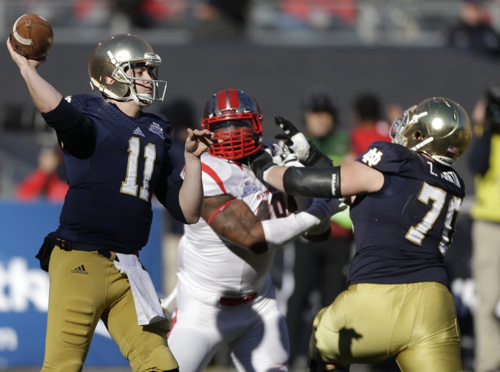Notre Dame quarterback Tommy Rees throws a pass as lineman Mark Harrell blocks Rutgers’ Marcus Thompson in the first half of the Pinstripe Bowl Saturday at Yankee Stadium.