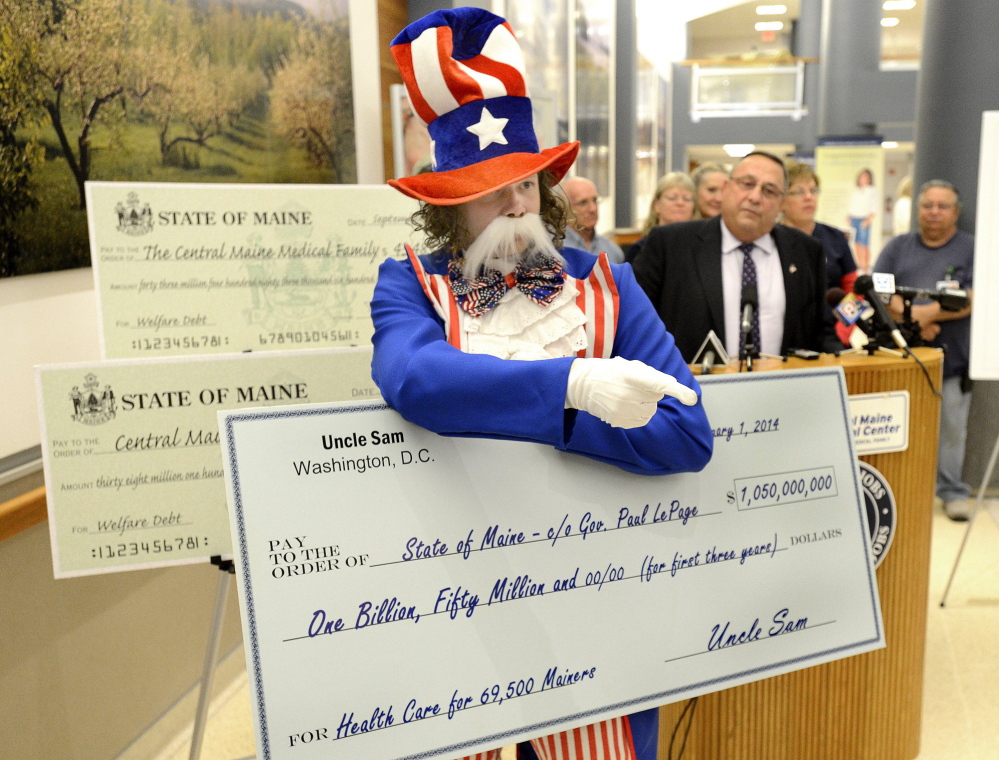 Paul Nickerson, dressed as Uncle Sam, disrupts a September media event where Gov. Paul LePage, background, presented a check to Central Maine Medical Center in Lewiston for backlogged Medicaid payments.