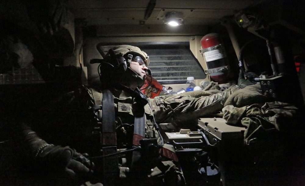 First Sgt. Andrew Pattle of Harrison, sitting in the back of a Mine-Resistant Ambush Protected vehicle, checks on the spacing of vehicles behind his truck as the 41-truck convoy leaves Forward Operating Base Shank with the destination of Bagram Air Field just after midnight on Dec. 24.