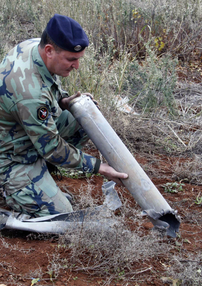 A Lebanese army soldier holds remains of a rocket that struck northern Israel, while inspecting an area in the southern village of Sarada, Lebanon, on Sunday.
