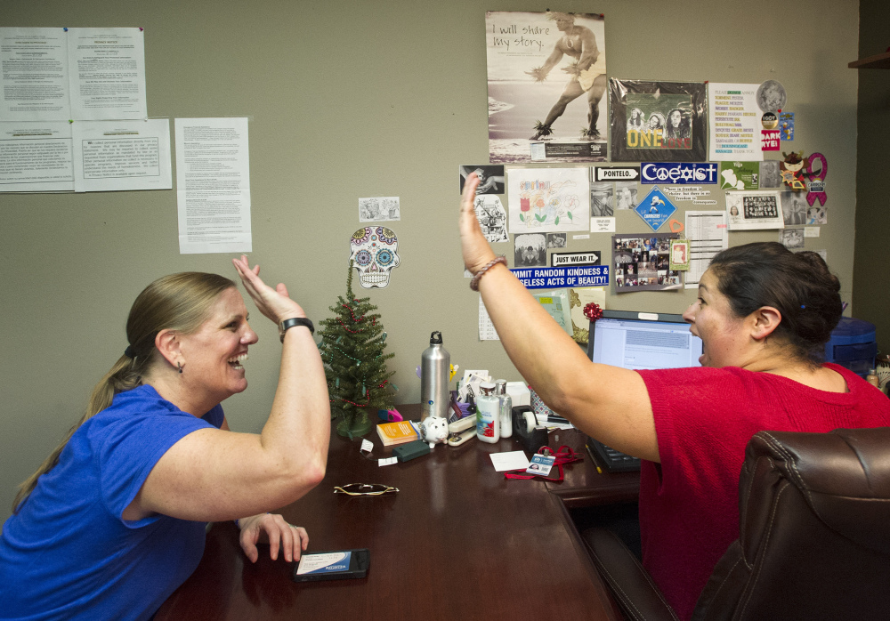 Lisa Donlea, left, and Susan Roberts, a certified enrollment officer, celebrate after working on Donlea’s federal health insurance exchange enrollment online for one hour and 47 minutes in Laguna Beach, Calif., last week. Enrollment surged in December.